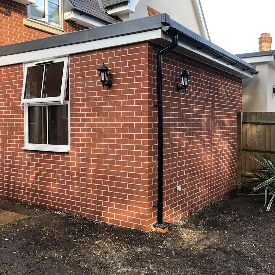 Brick-built modular extension corner with white uPVC window and exterior wall lights