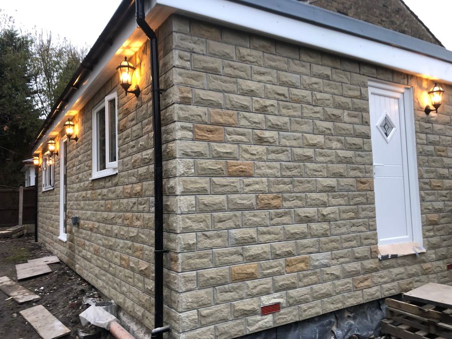 Stone-clad extension with composite door matching the original cottage
