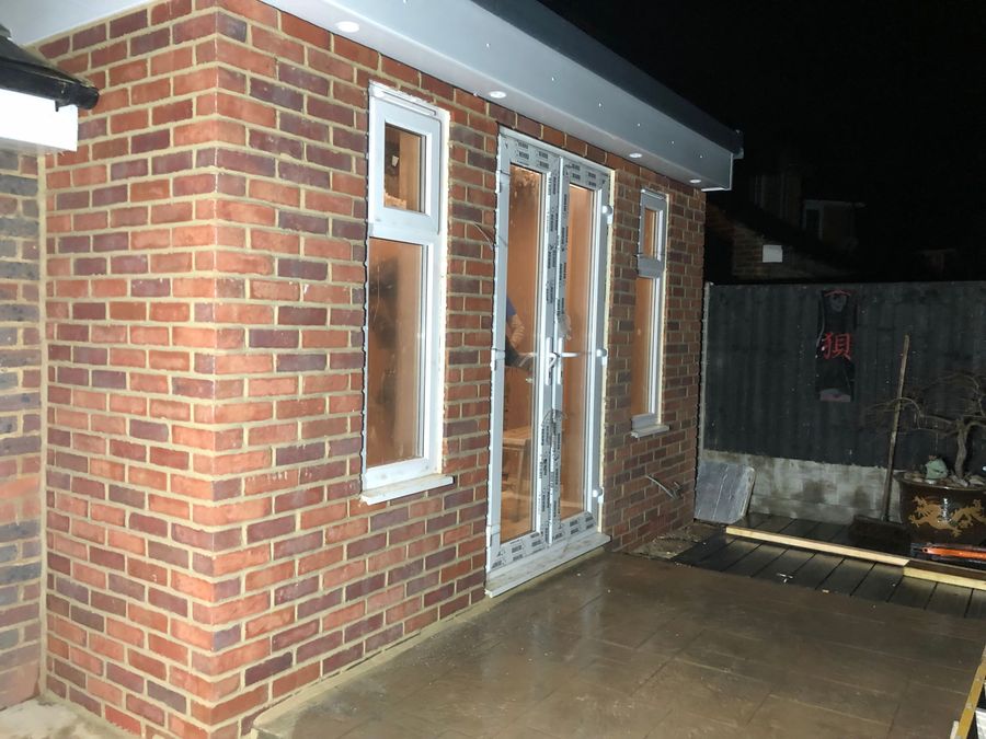 Brick modular extension with glazed doors photographed at dusk